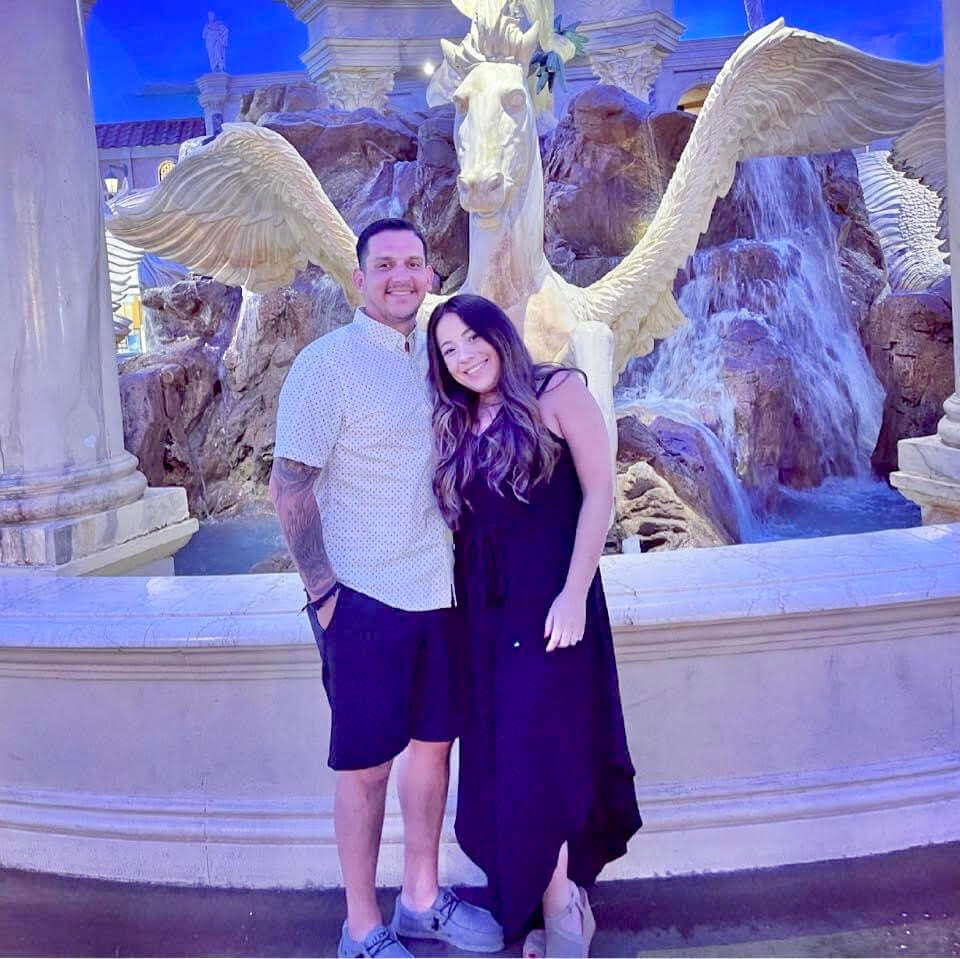 A young couple standing in front of a decorative fountain